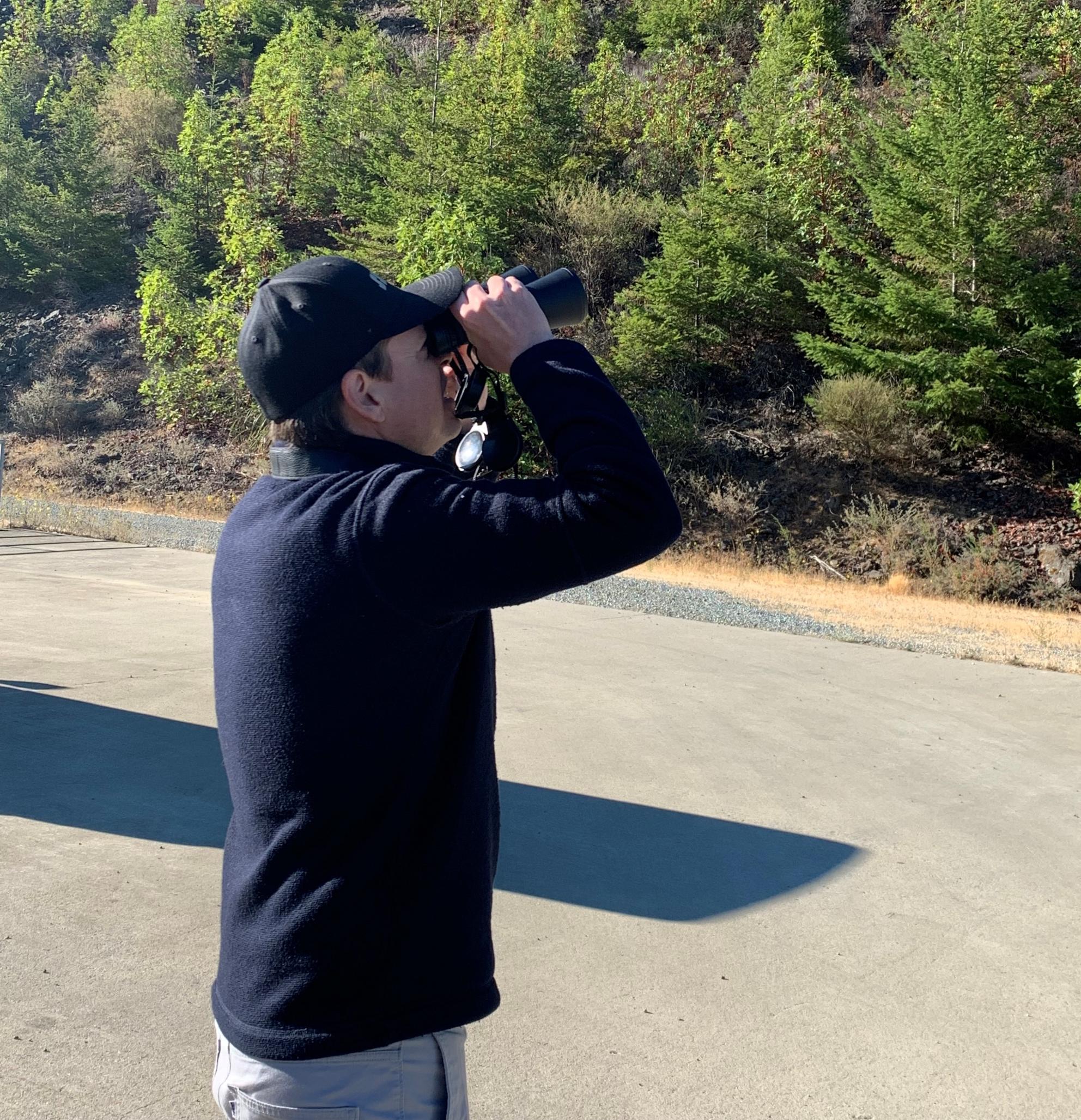 Jared Lewis looking through binoculars