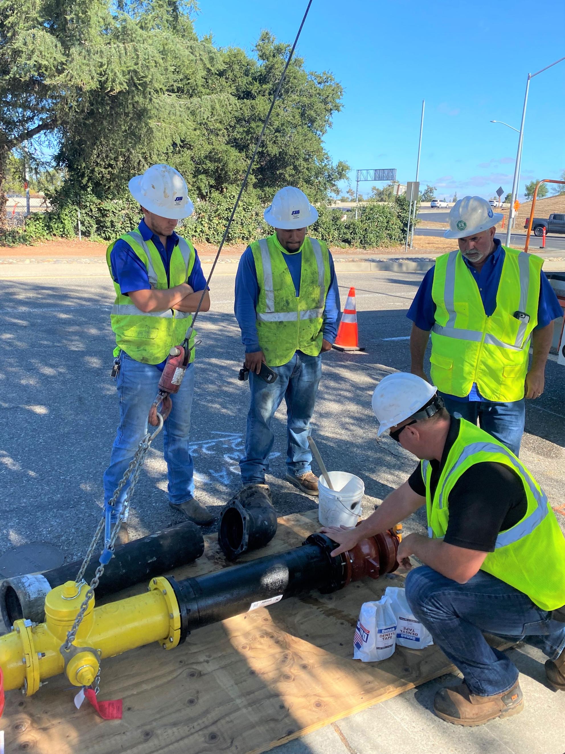 San Jose Water employees surrounding a fire hydrant that is about to be installed